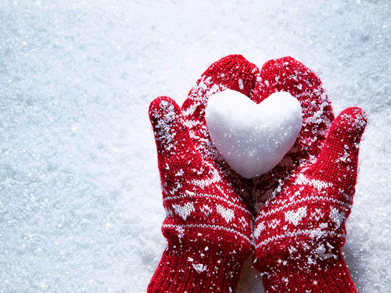 Life Extension, hands with red and white winter gloves on a snowy background and a snow heart in the hands